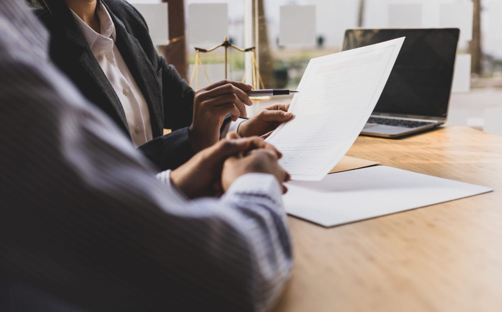 Two people sitting at a table with papers in front of them.