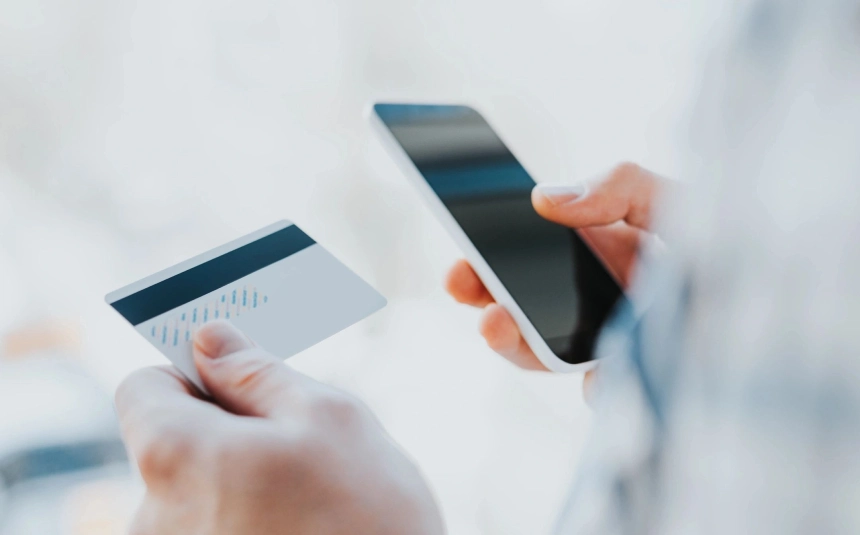 A person holding their phone and credit card.