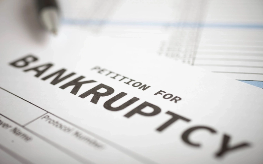 A person is writing on the paper of an unfiled bankruptcy petition.